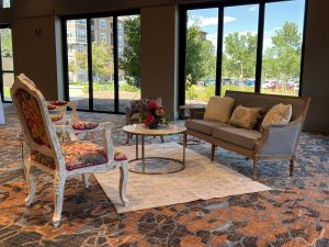 Photo of rented seating area in a lounge area.  Set-up includes a couch, 3 end tables, 3 chairs, an area rug, and pillows.  Seating should always be on your rental checklist.